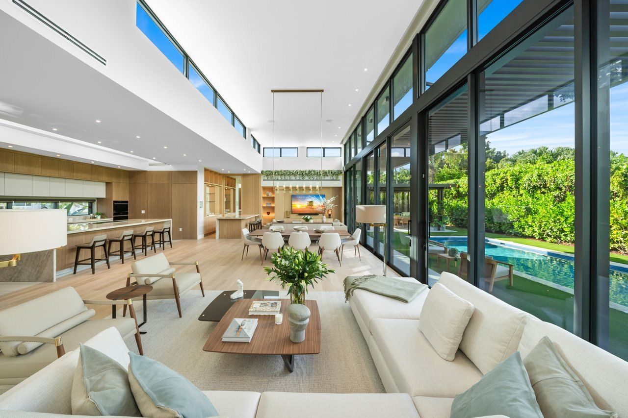 Double-height great room and kitchen with glass walls opening to the pool