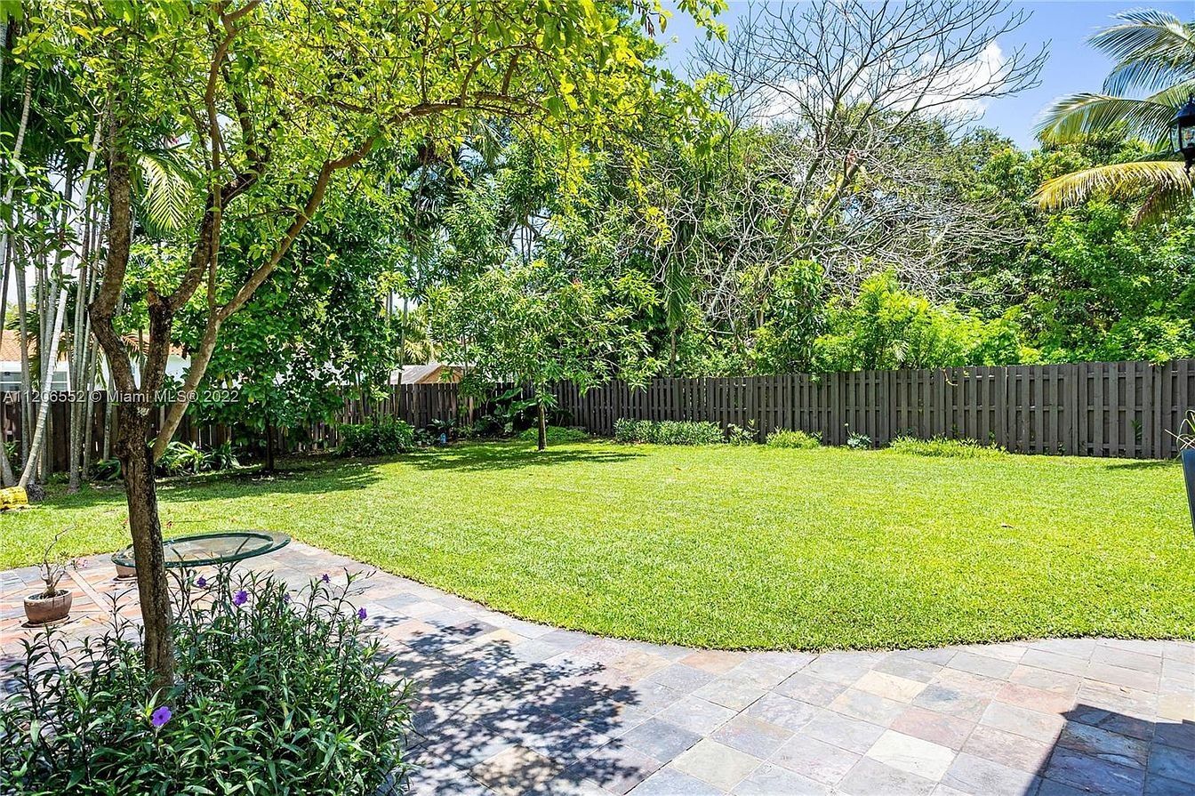 Back yard: a broad lawn with mature trees and a fenced boundary