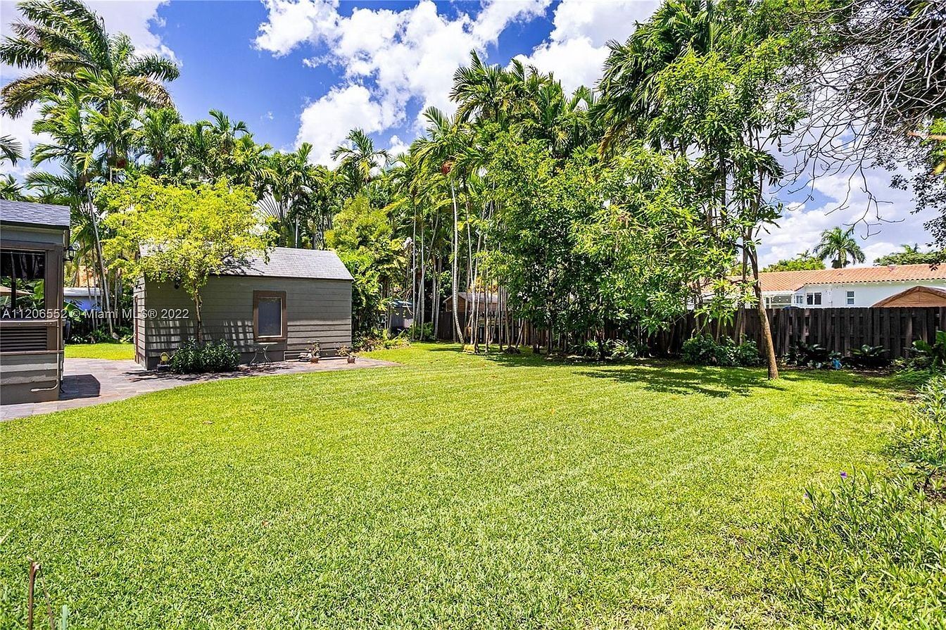 Deep rear yard with lawn running to a detached structure and the tree line